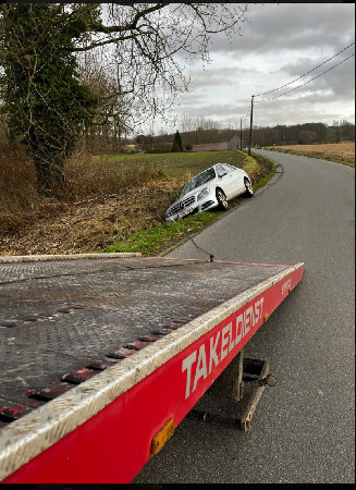 Witte auto in een gracht naast de weg